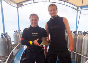Two divers holding a bell salvaged from a shipwreck.